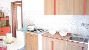 Une cuisine de taille réduite, équipée d’une cuisinière à gaz, d’un évier et d’un plan de travail.
