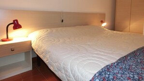Une chambre à coucher avec un lit, une table de chevet avec une lampe et une armoire.