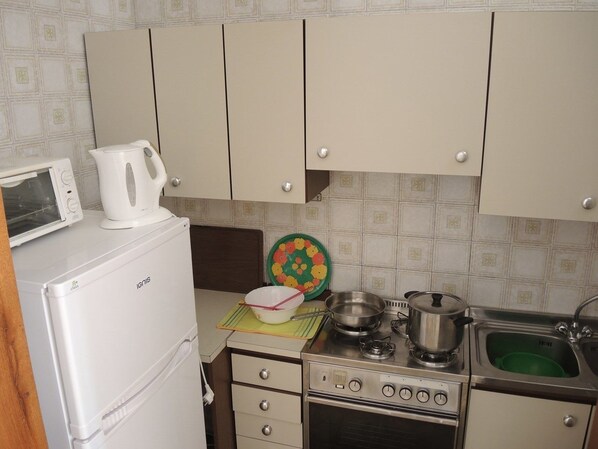 A compact kitchen with a white refrigerator, a microwave, a stove, and a sink. - Condominio Cavallino Sud (San Michele al Tagliamento)