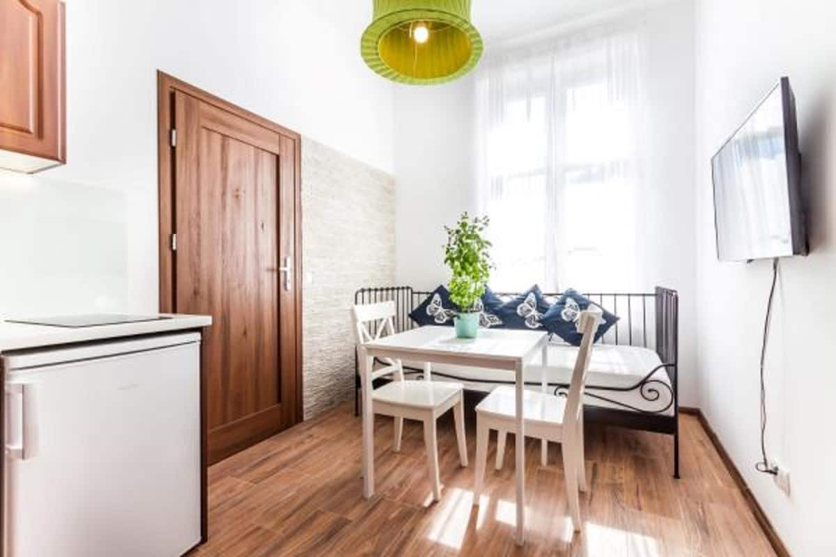 A compact kitchen with a refrigerator, wooden door, and a dining area with a table and chairs.