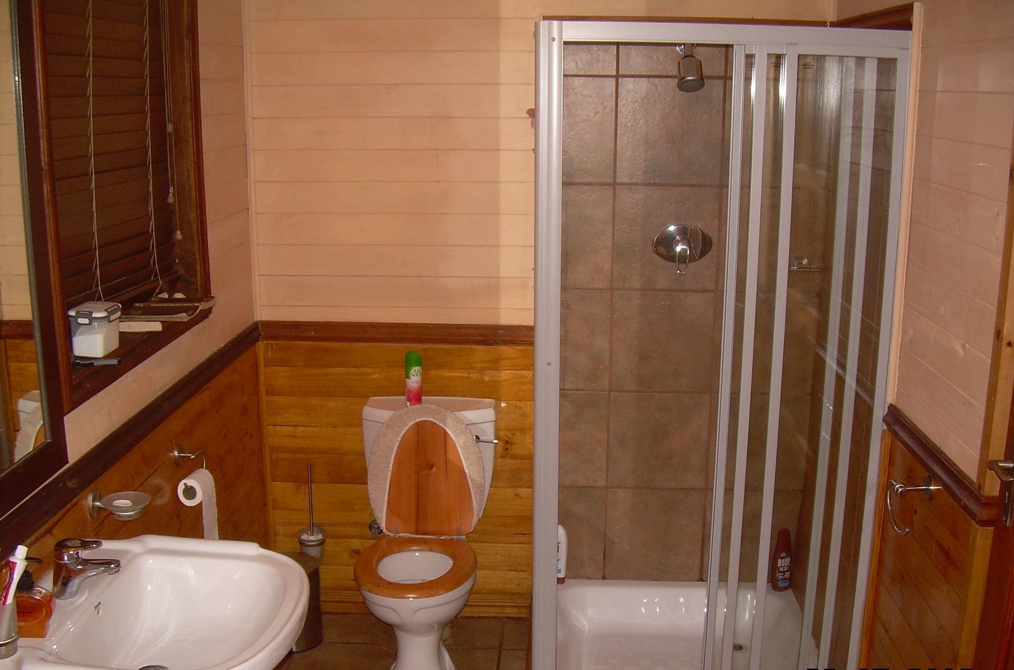 A bathroom with a wooden toilet, a sink, a bathtub, and a shower enclosure.