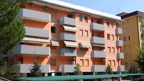A multi-story residential building with balconies, air conditioning units, and a green awning. - Condominio Lero (San Michele al Tagliamento)