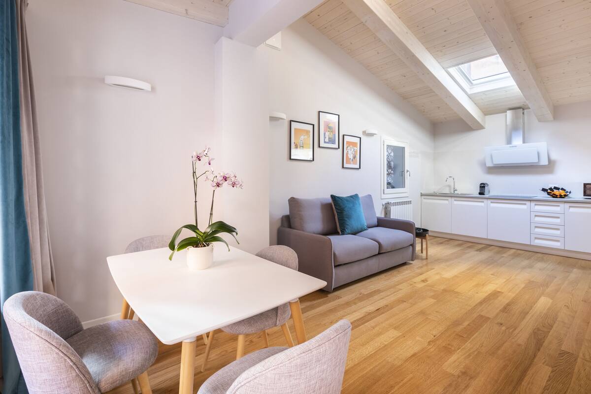 A modern living room with a dining table, sofa, and artwork on the walls.