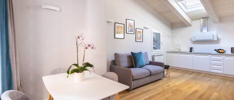 A modern living room with a dining table, sofa, and artwork on the walls.