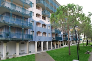 A multi-story hotel with balconies, a covered walkway, and a well-maintained lawn. - Condominio Terme (San Michele al Tagliamento)