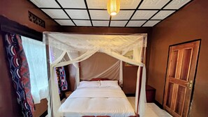 Una cama con dosel y mosquitera, una puerta de madera y un suelo de baldosas.