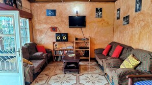 Una sala de estar con sofás estampados, una mesa de centro, una estantería y un televisor.