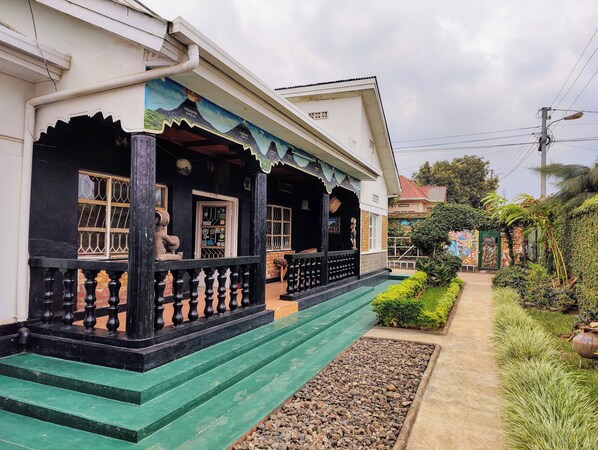 A traditional house with a porch, steps, and a garden. - Amahoro Guest House (Muhoza)