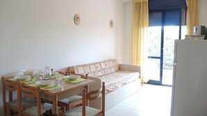 Un coin repas avec une table dressée pour quatre personnes, un canapé et un réfrigérateur.