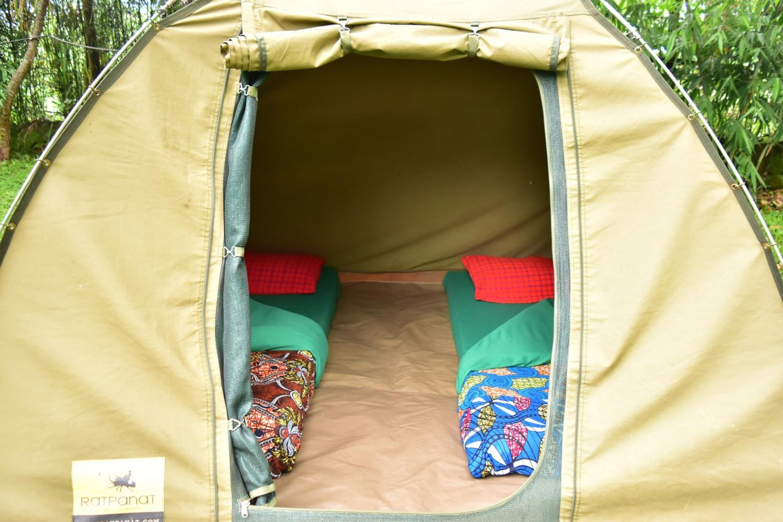 Una carpa con dos camas verdes y almohadas rojas, un interior color beige y una etiqueta que dice "RATPANAT.COM".