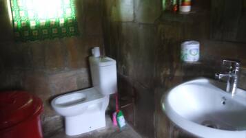 A bathroom with a toilet, sink, and a red trash bin.