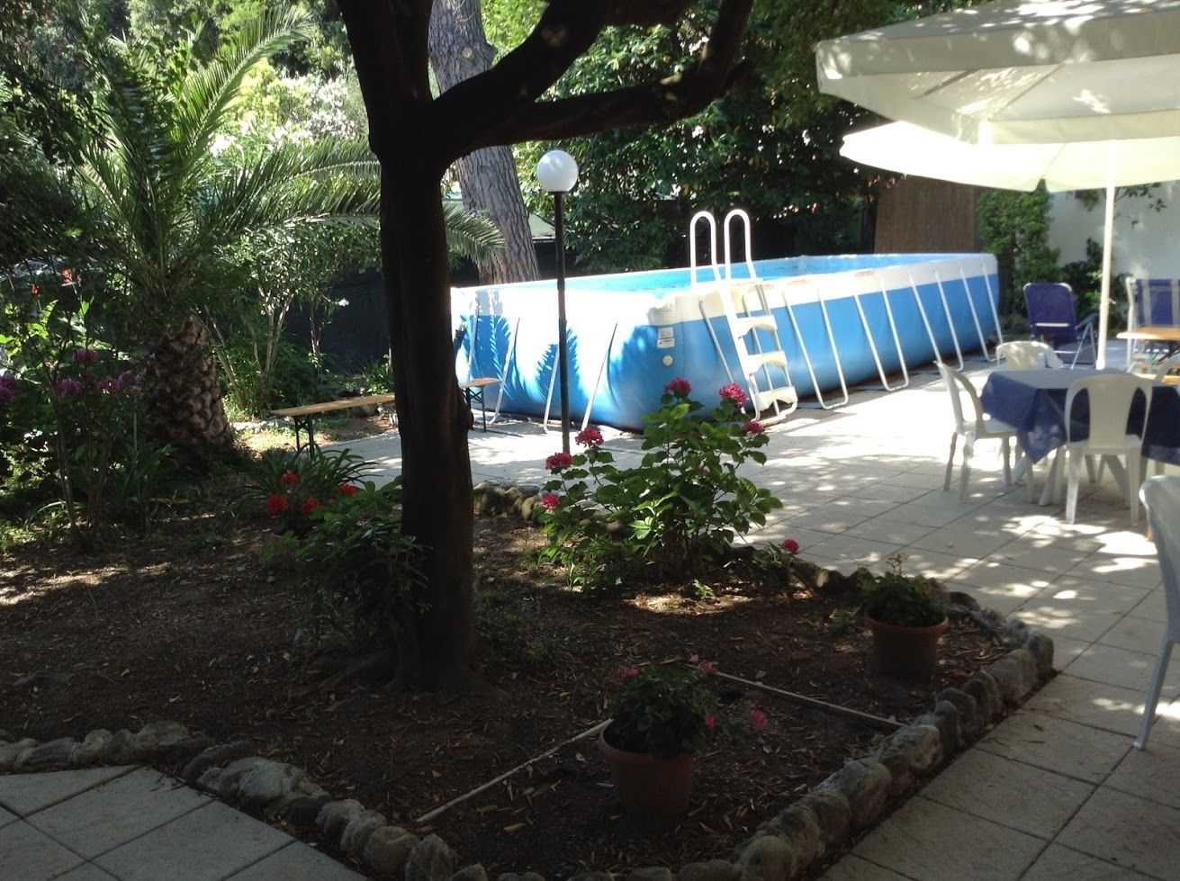 A pool area with a ladder, chairs, and potted plants.