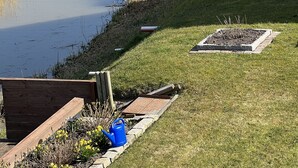 Un barrio residencial con un estrecho canal de agua, orillas cubiertas de césped y una terraza de madera.