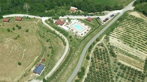 Vue aérienne d’une propriété comprenant une piscine, plusieurs bâtiments et un vignoble.