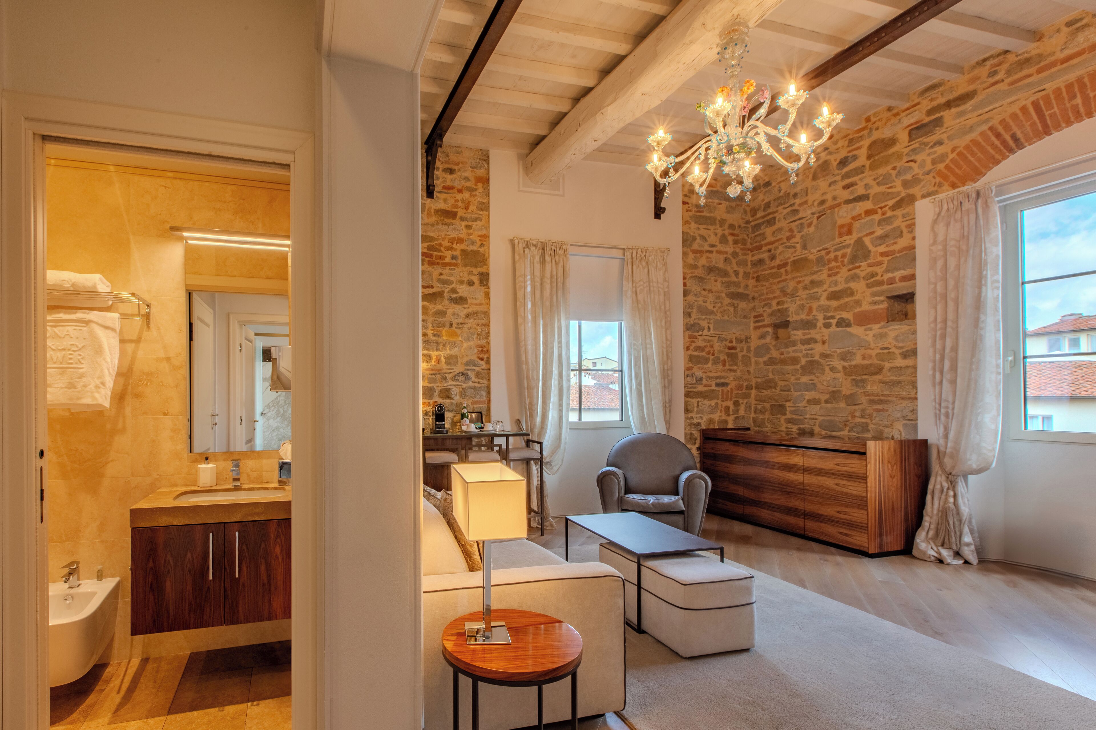 A spacious living area with a stone wall, a chandelier, a sofa, a coffee table, and a wooden cabinet.