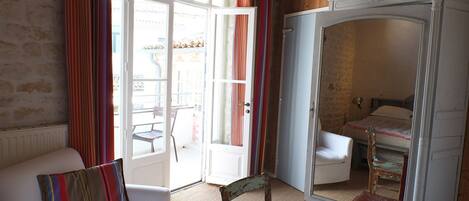 A room with a white sofa, a wooden chair, a small table, and a wardrobe.