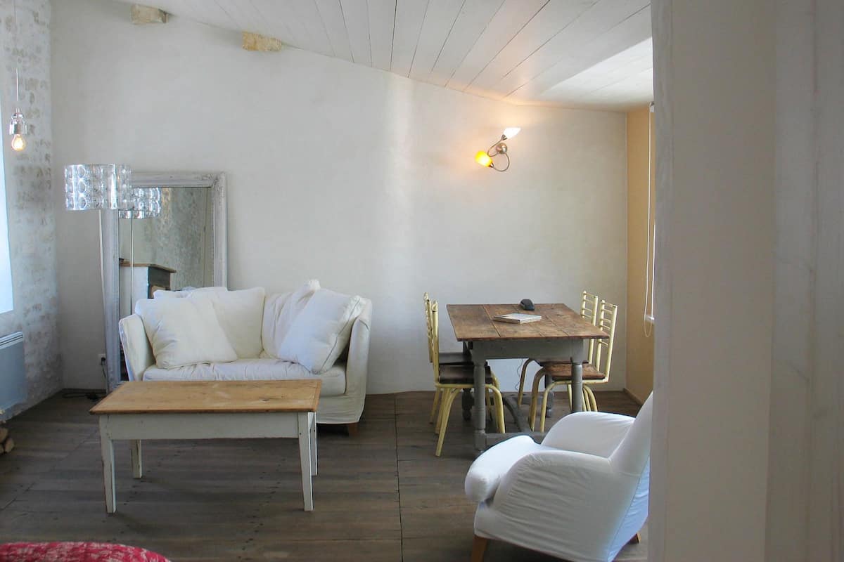 Ein gemütliches Wohnzimmer mit einem Holztisch, einem weißen Sofa und einem Essbereich mit Holztisch und Stühlen.