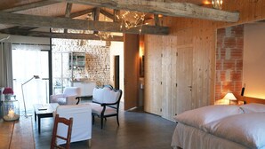 A cozy room with a bed, a wooden ceiling, a stone wall, and a dining area with a table and chairs. - Hôtel Le Sénéchal (Ars-en-Re)