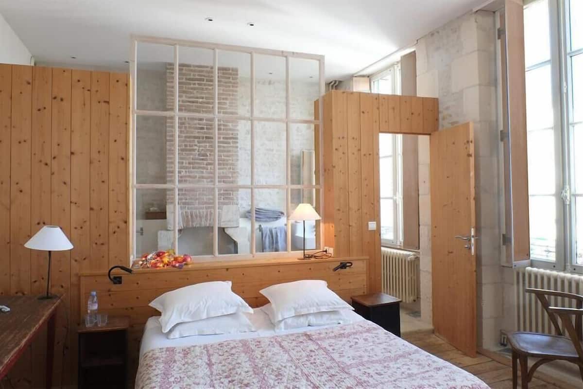 Ein Schlafzimmer mit einem großen Bett, Holzwänden, einem Fenster und einem Spiegel.