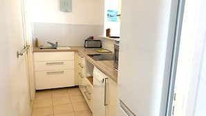 A compact kitchen with white cabinets, a sink, a toaster, and a dishwasher. - Spacious apartment with WIFI, 2 bedrooms, downtown Perros-Guirec, near beaches (Perros-Guirec)