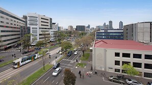 A cityscape with modern buildings, a tram, and a parking lot.