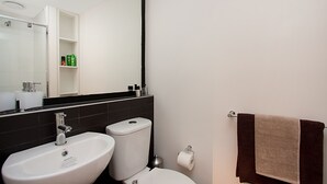 A modern bathroom with a white sink, a toilet, and a large mirror.