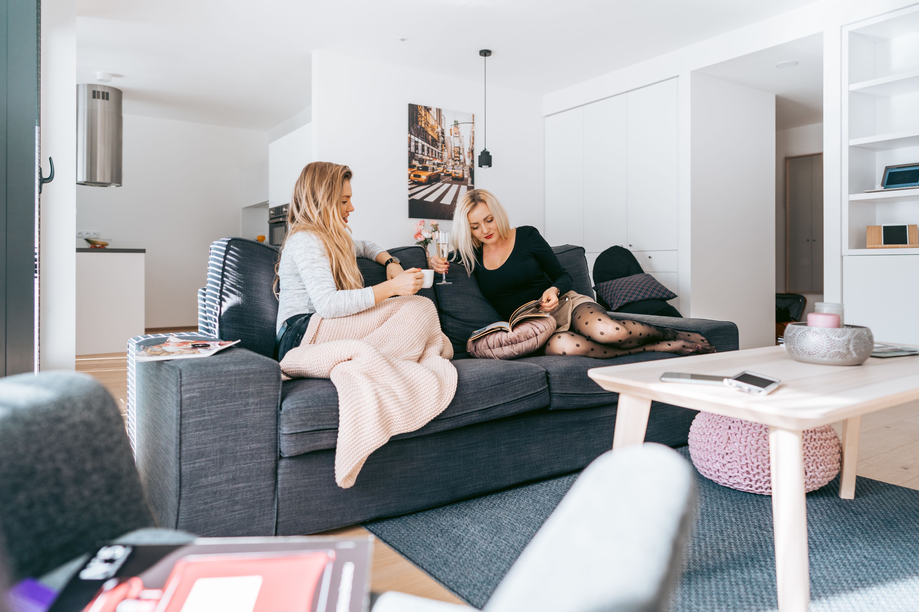 A modern living room with a grey sofa, a coffee table, and a kitchen in the background.