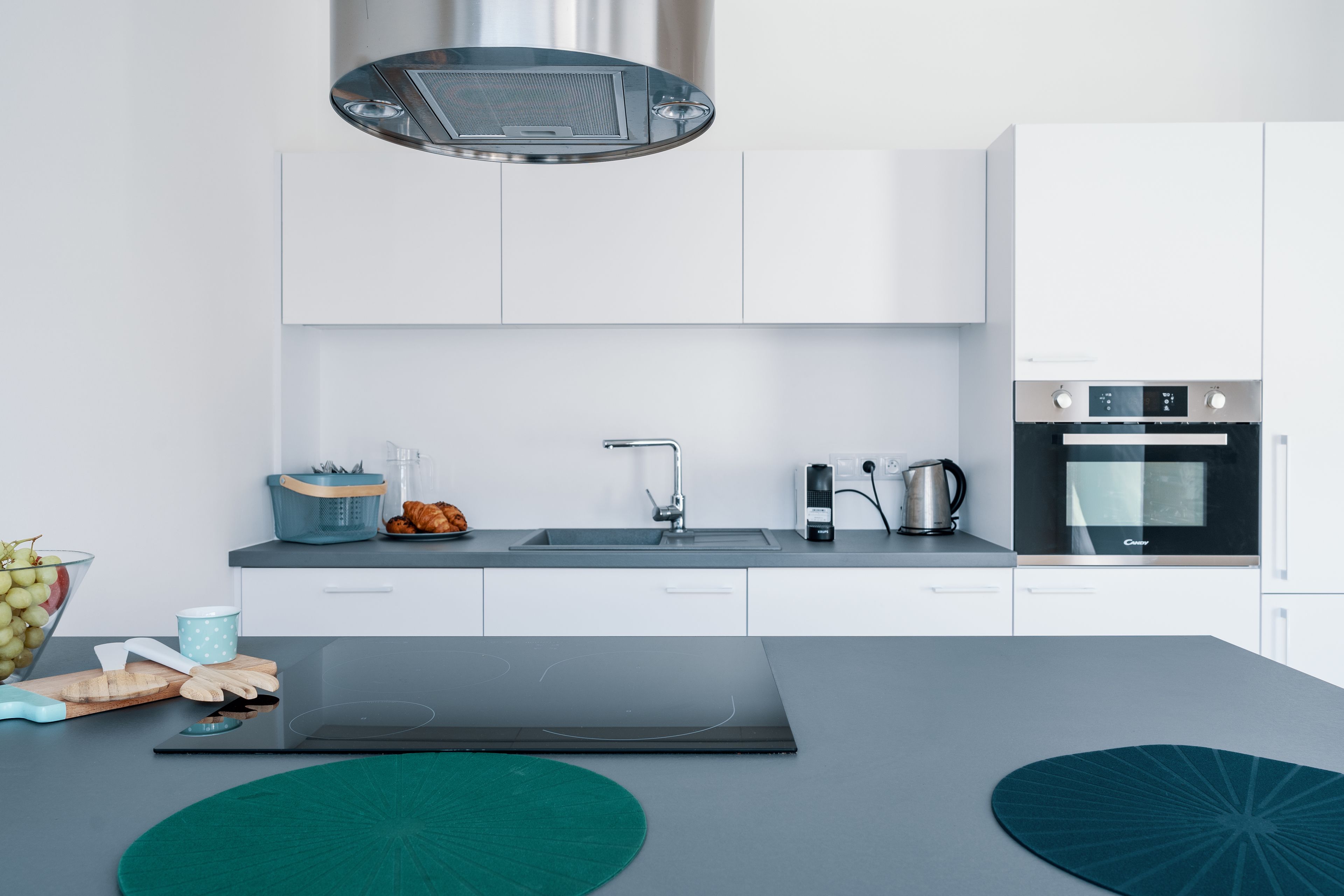Una cocina moderna con armarios blancos, encimera negra y electrodomésticos de acero inoxidable, incluyendo estufa y horno.