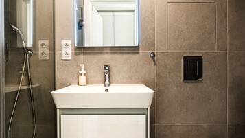 A modern bathroom with a shower, sink, toilet, and a mirror above the sink.