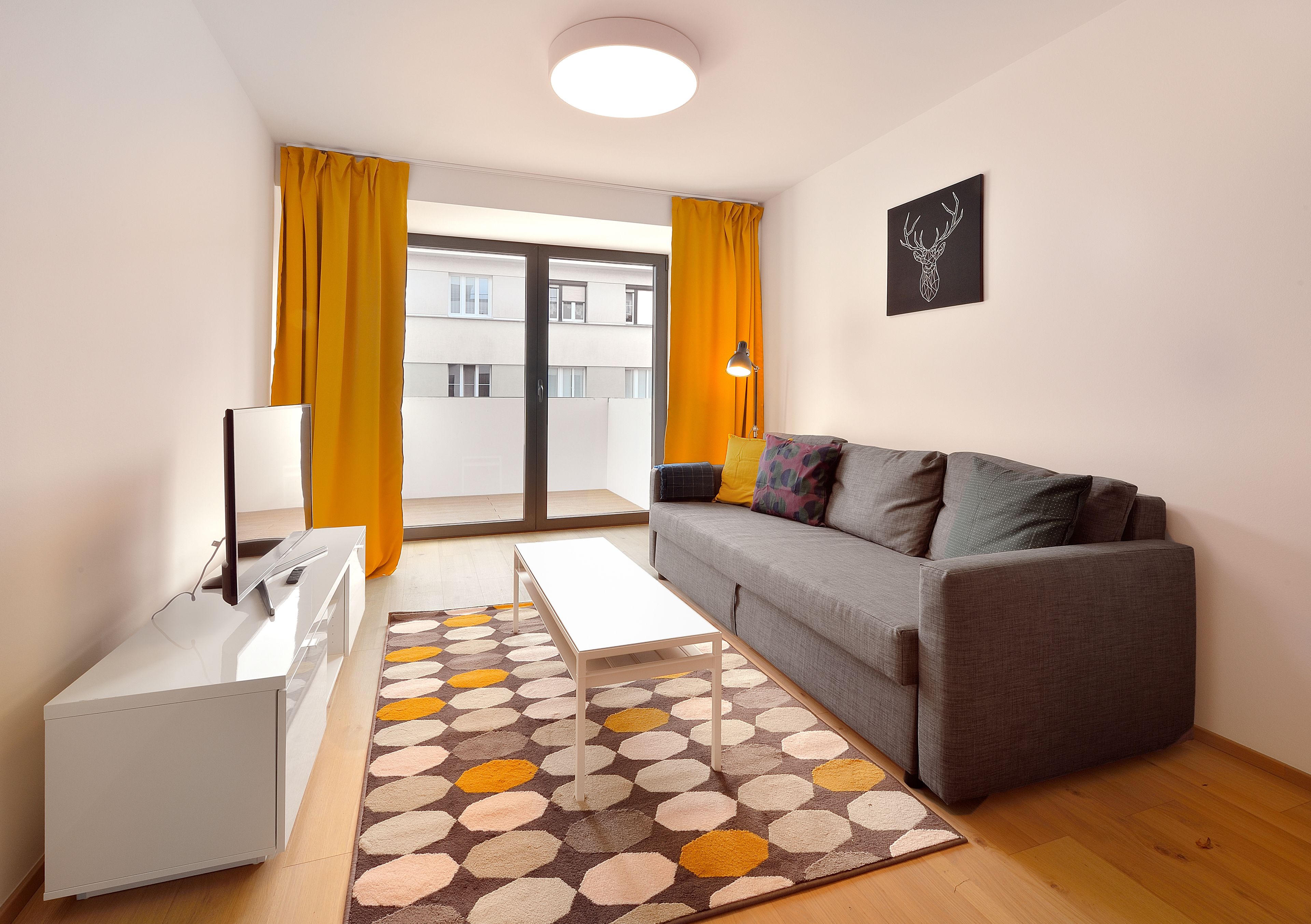 A modern living room with a grey sofa, a white coffee table, and a patterned rug.