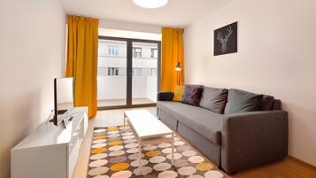 A modern living room with a grey sofa, a white coffee table, and a patterned rug.