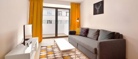 A modern living room with a grey sofa, a white coffee table, and a patterned rug.