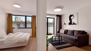 A modern room with a bed, a sofa, a small table, and a potted plant. - Smart & Green Living by Ambiente (Bratislava)