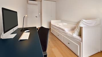Een slaapkamer met een bureau, computer en bed.