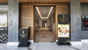 The entrance to a spa with a modern design, featuring a reception desk, seating area, and a visible corridor leading inside.
