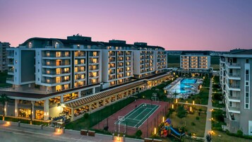 Un moderno complejo hotelero con varias torres, una piscina y una cancha de tenis.