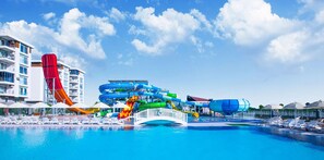 A water park with a large pool, a red water slide, and a multi-level water slide structure. - Greenwood Suites Resort (Antalya)