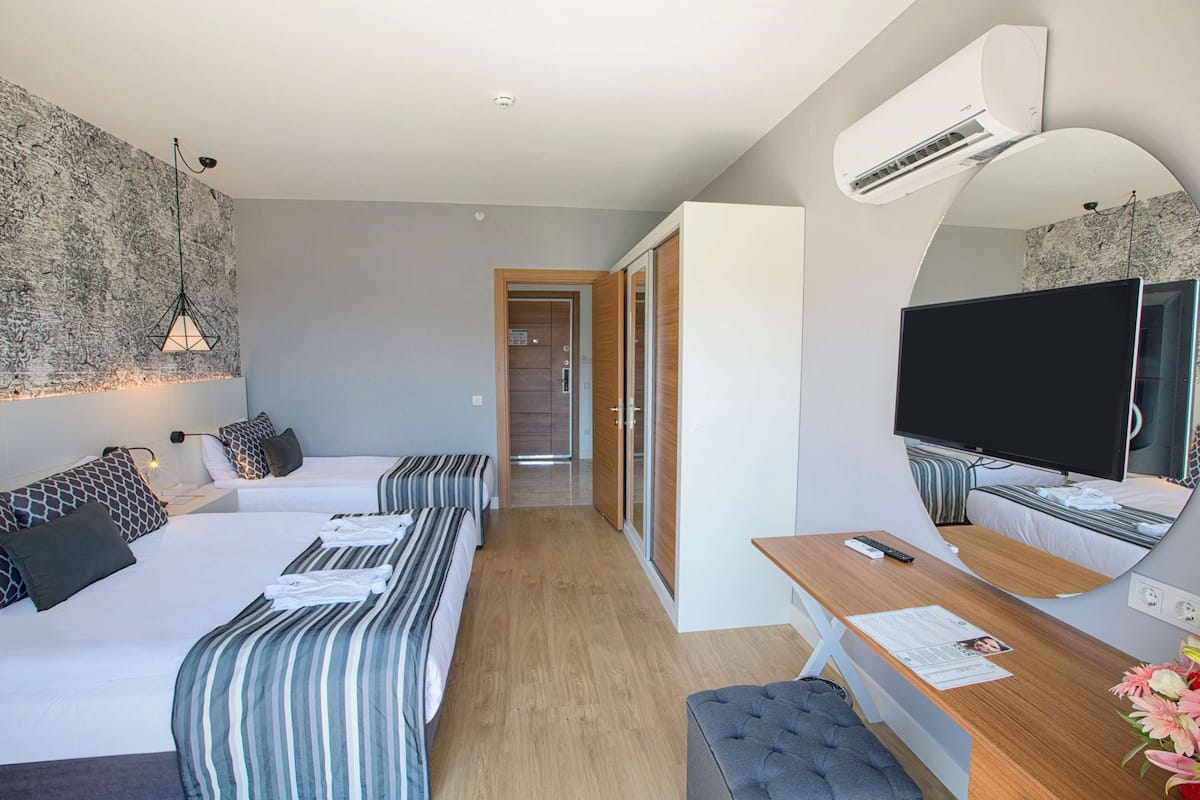 Une chambre d’hôtel moderne équipée de deux lits, d’un bureau, d’une télévision et d’un grand miroir.