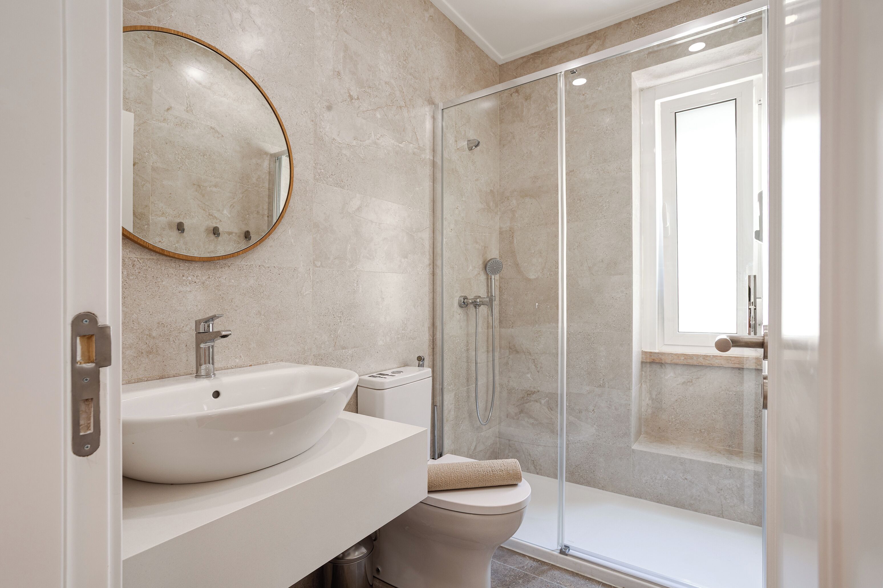 A modern bathroom with a large sink, toilet, and glass-enclosed shower.