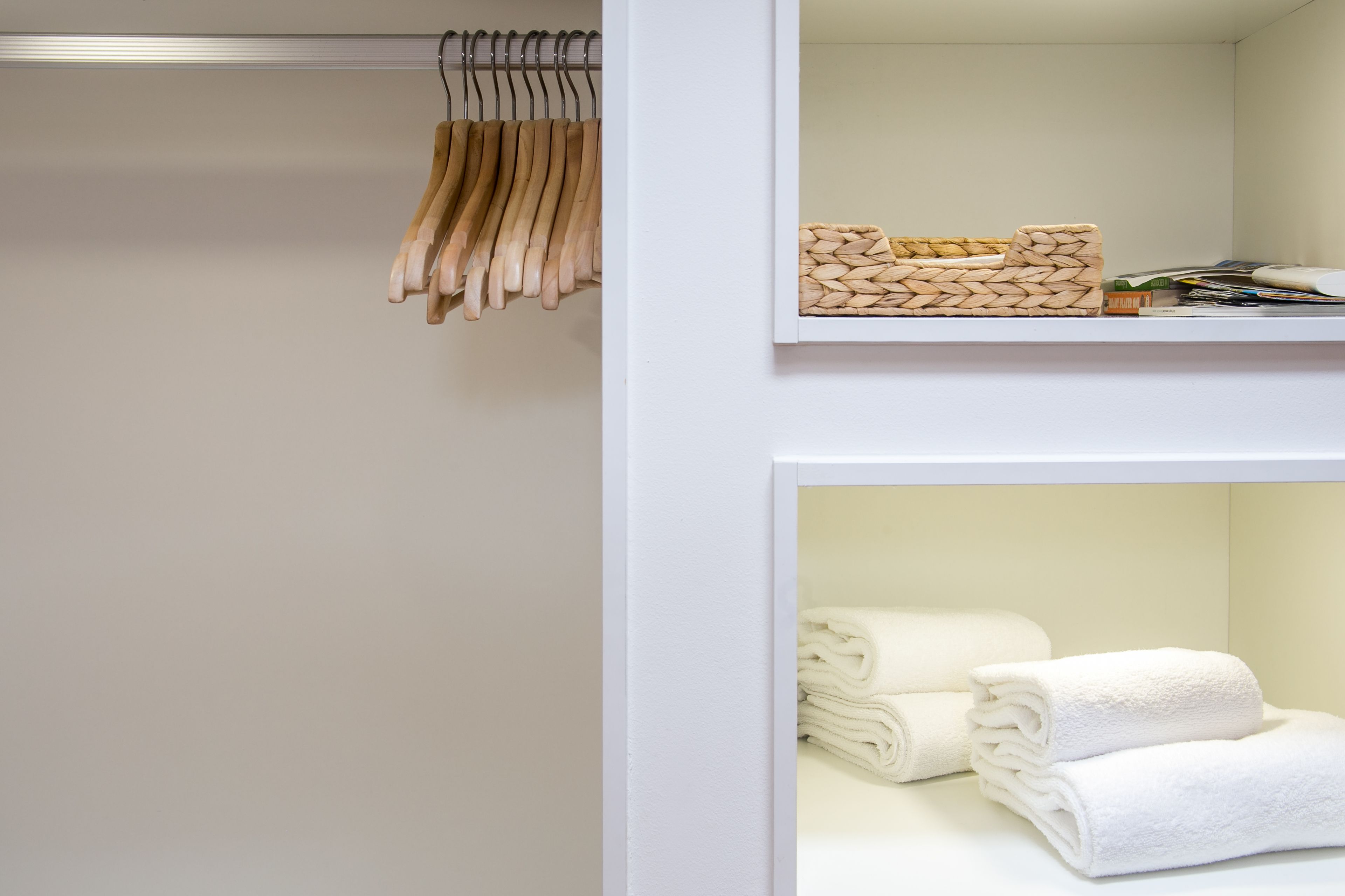 A neatly organized closet with wooden hangers and folded towels.