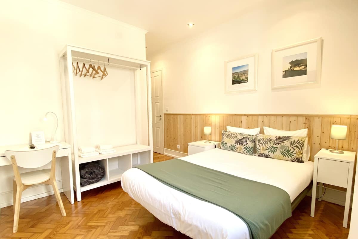 Une chambre à coucher comprenant un lit, un bureau, une chaise, une armoire et deux lampes de chevet.