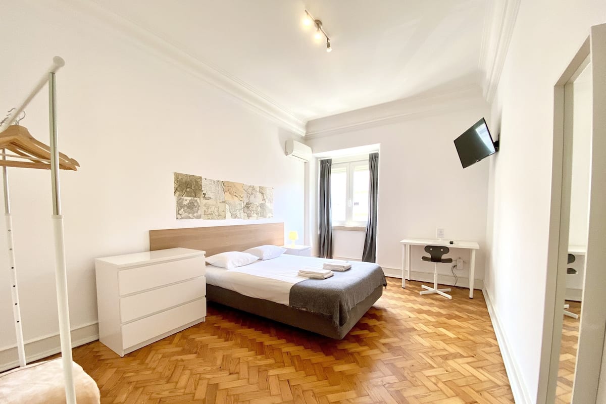 Une chambre à coucher avec un lit, un bureau, une chaise, une armoire et une carte accrochée au mur.