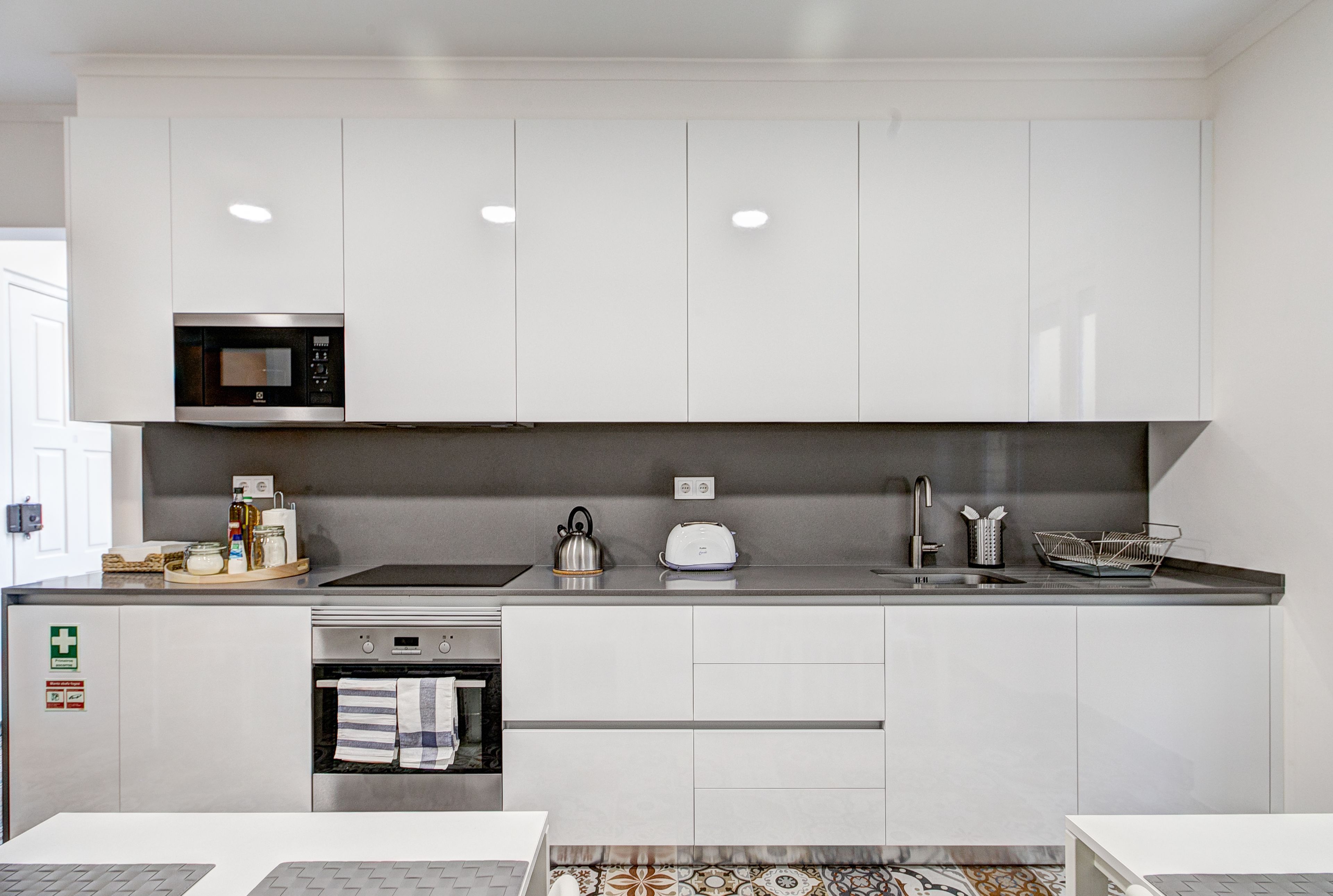 A modern kitchen with white cabinets, a microwave, a kettle, and a toaster.
