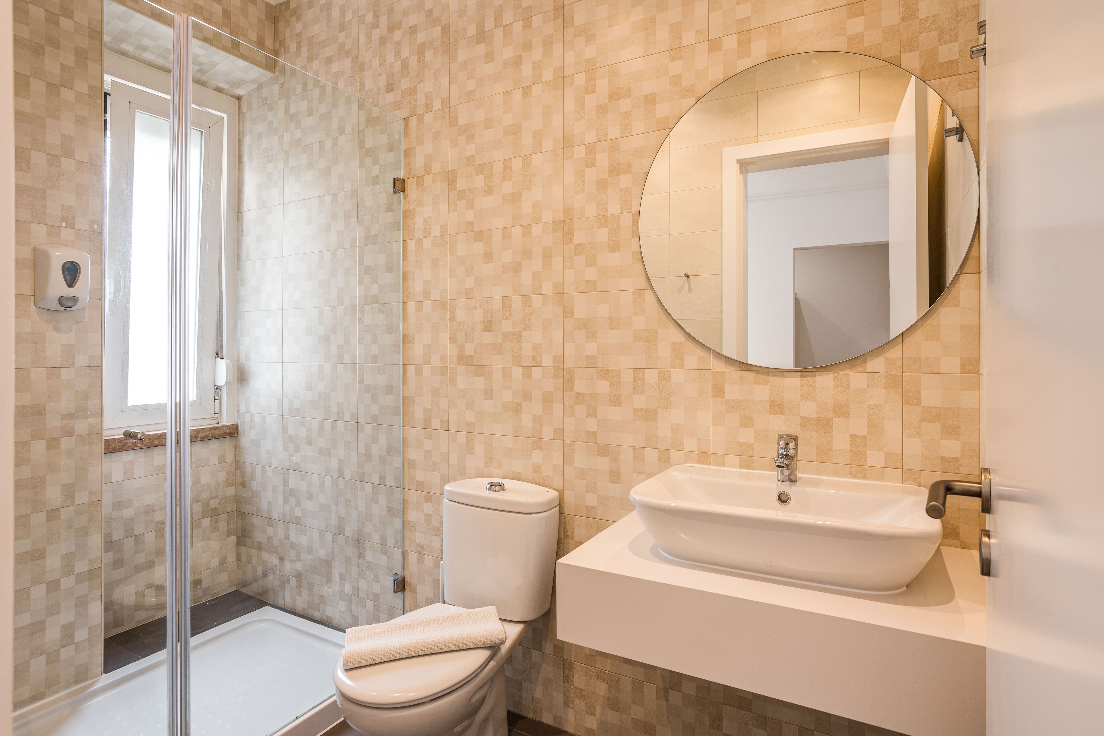 Ein modernes Badezimmer mit Duschkabine aus Glas, Toilette und Waschbecken mit Spiegel darüber.