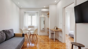 Een modern interieur met een bank, eettafel, stoelen, een televisie en een spiegel.