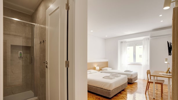 Een hotelkamer met een douche, twee bedden, een bureau en een stoel.