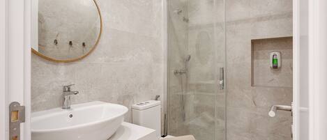 Une salle de bain équipée d’un lavabo, de toilettes et d’une douche à parois de verre.