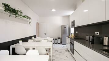 Een moderne keuken met witte kasten, een roestvrijstalen koelkast en een zwart aanrecht.