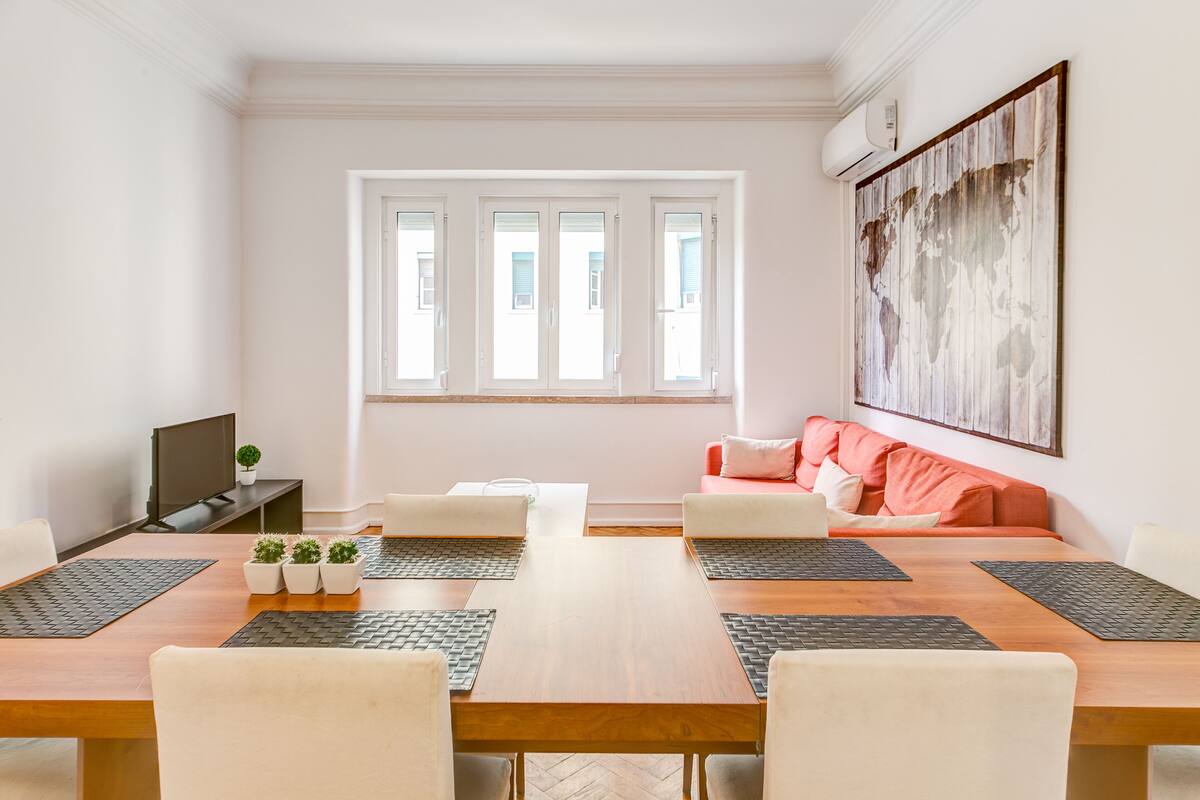 Un salon moderne avec une table à manger en bois, des canapés blancs et un grand tableau abstrait accroché au mur.
