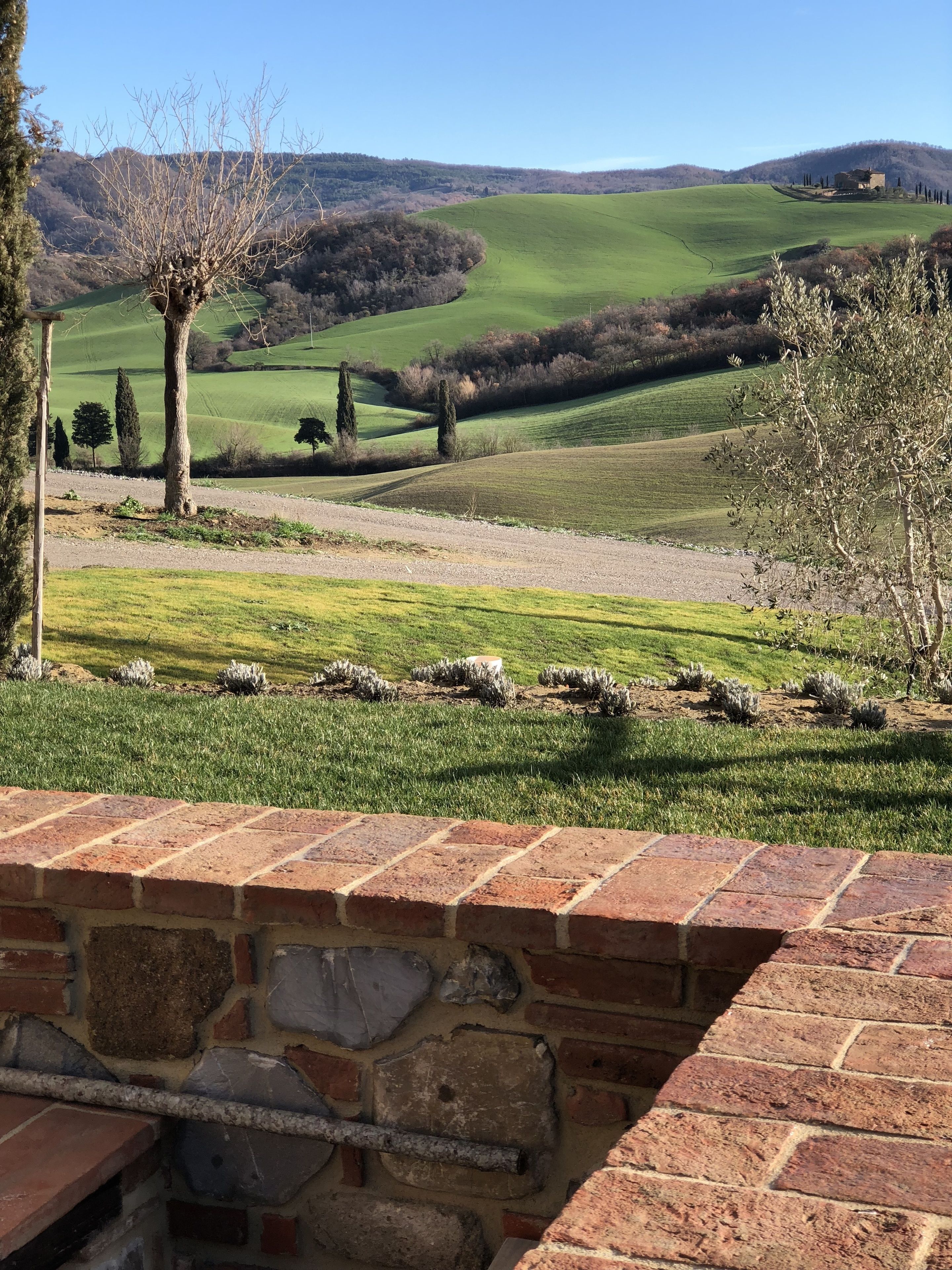 A rural landscape with rolling green hills, a stone wall in the foreground, and a distant building on a hill.